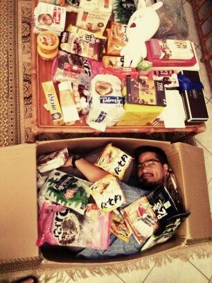 Jisu liegt in einer Box voller koreanischer Lebensmittel und Snacks